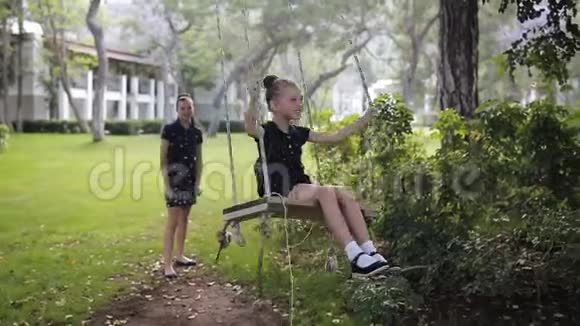 姐姐在阳光下的树下摇着女儿女孩笑高兴公园里的家庭乐趣视频的预览图