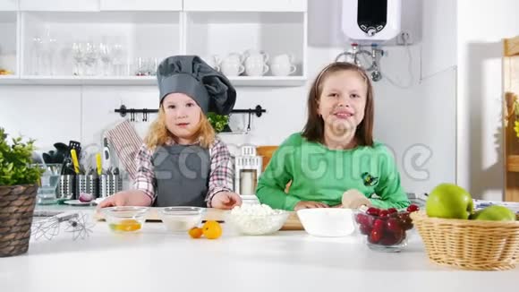 两个学龄前小女孩面包师在烹饪奶酪蛋糕和甜点时玩得很开心视频的预览图