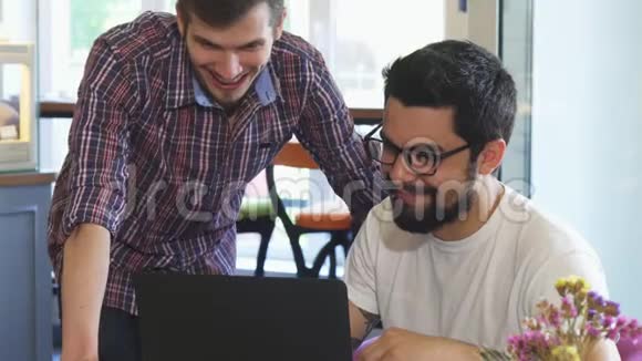 两个年轻人一起在咖啡店用笔记本电脑视频的预览图