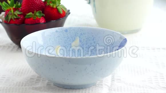 玉米片倒入碗中用牛奶和草莓作为早餐视频的预览图