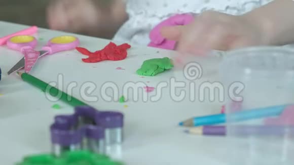 一个小女孩玩橡皮泥雕刻一个图形桌面上有图形和彩色铅笔视频的预览图