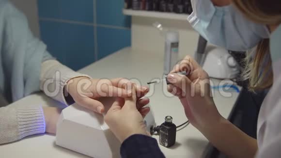 沙龙的指甲护理主人在顾客的指甲上涂上凝胶漆视频的预览图