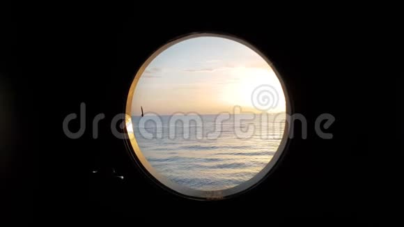 日落时平静海面上帆船舷窗的宁静景色视频的预览图
