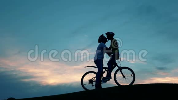 在日落时骑自行车亲吻浪漫的年轻夫妇视频的预览图