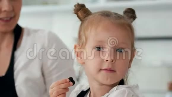 快乐的小女孩舔着浆果看着相机视频的预览图