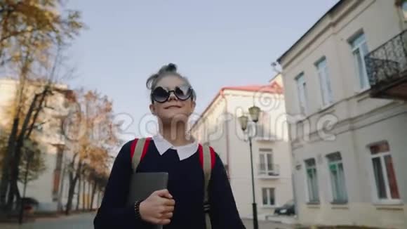 漂亮的时髦少女走在老城街上微笑着手拿手提电脑的红包女学生视频的预览图