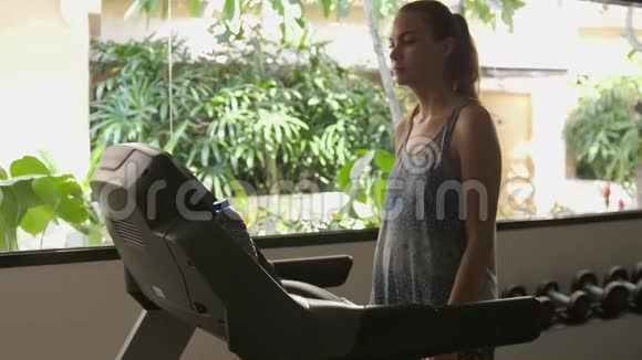 漂亮的白种人女孩在运动健身房的跑步机上行走慢动作3840x2160视频的预览图