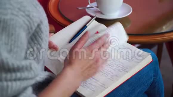 坐在桌旁拿着记事本喝咖啡的女孩视频的预览图