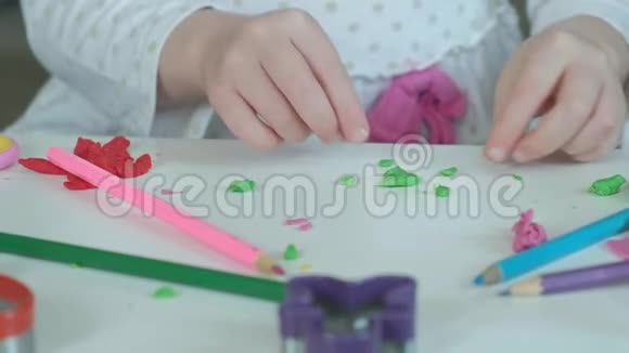 一个小女孩玩橡皮泥雕刻一个图形桌面上有图形和彩色铅笔视频的预览图