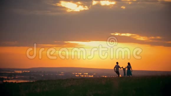 快乐的传统家庭步行户外妈妈爸爸和小儿子在夏季草地日落视频的预览图