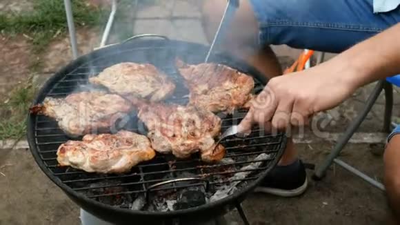 人翻来覆去的大块美味的肉牛排在烧烤炉上烤过煤视频的预览图
