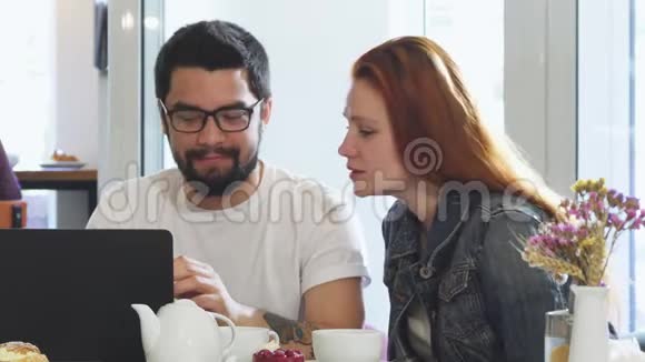 可爱的一对夫妇在咖啡店吃早餐时一起使用小玩意视频的预览图
