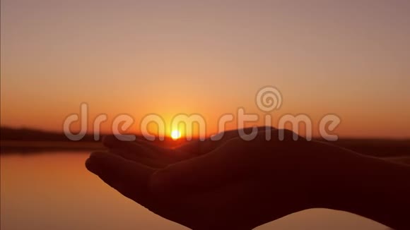 双手捧着太阳在手心美丽的晚霞在水面上特写视频的预览图
