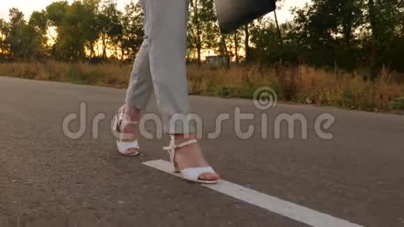 细长的腿在沥青上行走穿白鞋的女孩在上班的路上她手里拿着一个黑色公文包慢慢视频的预览图