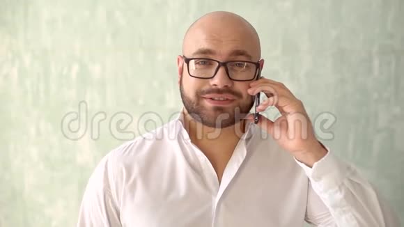 近距离的商人胡子脸在手机上交谈一个穿着白色衬衫的时髦男人在手机上说话视频的预览图