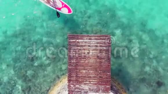 冲浪板上的女孩在码头附近游泳最纯净的绿松石水热带岛屿上的天堂自然视频的预览图