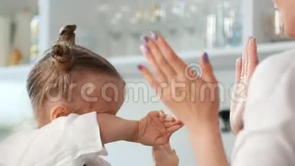 快乐的小女孩和妈妈在厨房拍手视频的预览图