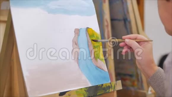 艺术家的手一位女艺术家用画笔绘制画布坐在画架上在画架上进行笔触视频的预览图