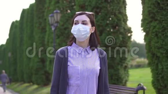 戴着医用口罩的女孩在公园里慢悠悠视频的预览图