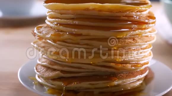 美味可口的新鲜薄煎饼等着在桌上吃在木制的表面上撒上融化的金色蜂蜜视频的预览图