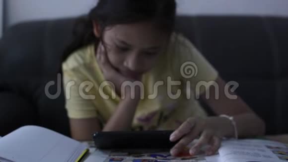 小女孩在做作业时使用手机视频的预览图