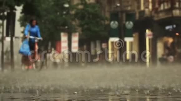 城市街道大雨天气的背景实时骑自行车的女人正在经过模糊的波克自然资源视频的预览图
