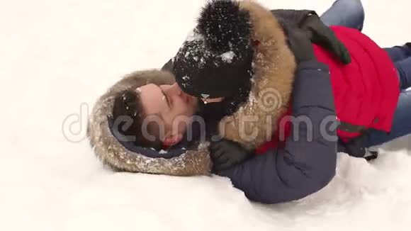 恋爱中的情侣躺在冬天公园的雪地上视频的预览图