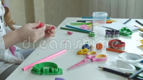 一个小女孩玩橡皮泥分成几小块桌面上是图形和彩色铅笔视频的预览图