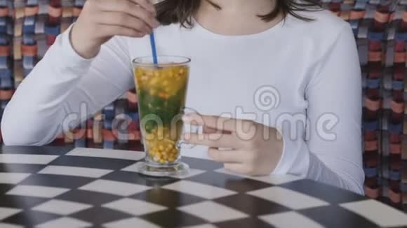 美丽的女孩在咖啡馆里用小管搅拌口味饮料慢慢地视频的预览图