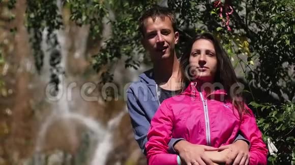 一对恋人站在瀑布上蜜月亲吻山脉的背景家庭观念夫妻俩视频的预览图
