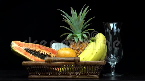 在玻璃杯中倒入橙汁的细节在篮子中倒入异国风味的水果视频的预览图