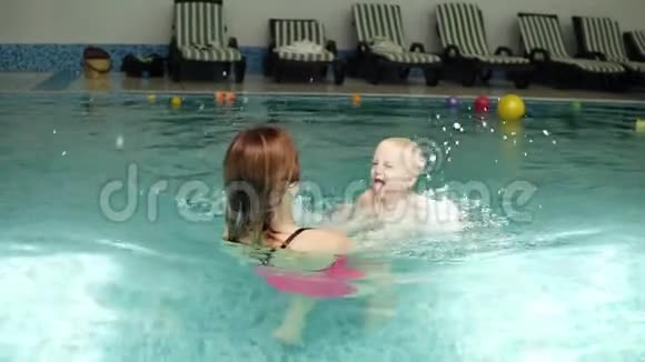 可爱的宝宝和他妈妈一起上游泳课健康的家庭教他们的孩子在游泳池游泳青年视频的预览图
