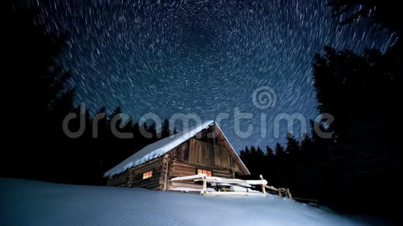 时间流逝在冬天的森林里星星在木屋上盘旋视频的预览图