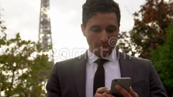 穿西装的人在埃菲尔铁塔旁边的智能手机上使用应用程序视频的预览图
