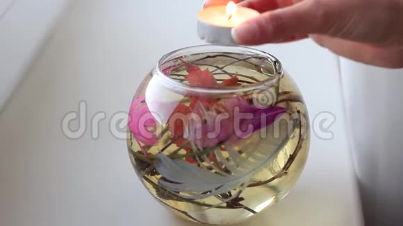 女人手把蜡烛放在装有水和装饰的瓶子里视频的预览图