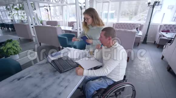 在使用现代计算机技术进行个人教育期间轮椅上的智能残疾学生男子与辅导妇女一起视频的预览图