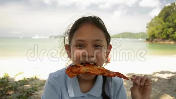 可爱的女孩在海滩上吃烤鸡视频的预览图