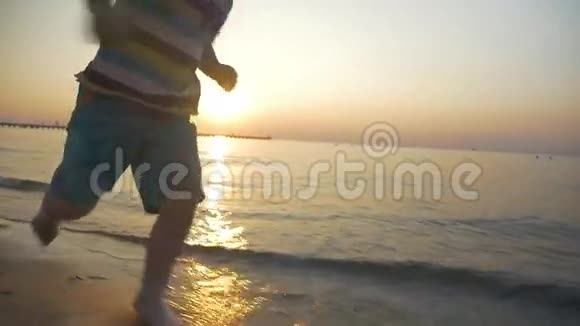 赤脚小孩日落时在海水中奔跑视频的预览图