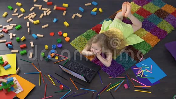 可爱的卷发女孩在笔记本电脑上使用教育软件在家学习数字视频的预览图