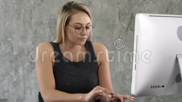 微笑着漂亮的年轻商务女性戴着眼镜坐在工作场所视频的预览图