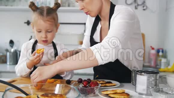小女孩和她妈妈一起切水果装饰自制的干酪薄饼视频的预览图