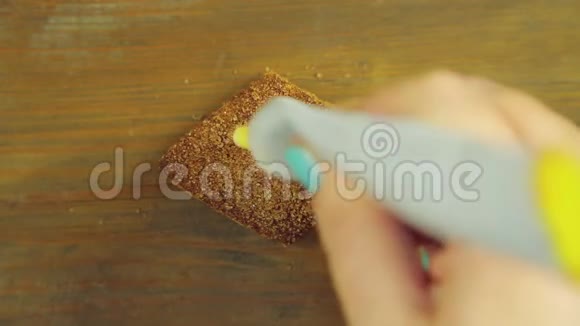一只手拿着一管烹饪颜料在巧克力饼干上画了三根黄色的颜料视频的预览图