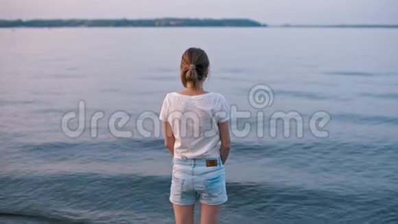 年轻苗条的女人看着水想着夕阳视频的预览图