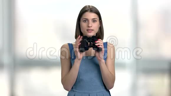 年轻的好奇的女人带着双筒望远镜视频的预览图