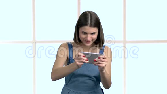 可爱有趣的女人在智能手机上玩游戏视频的预览图