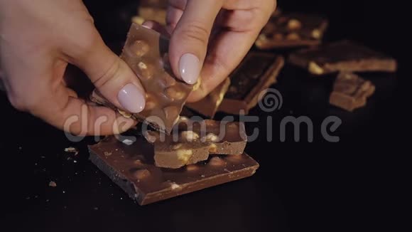 女人用坚果打破黑色巧克力棒特写镜头慢动作视频的预览图