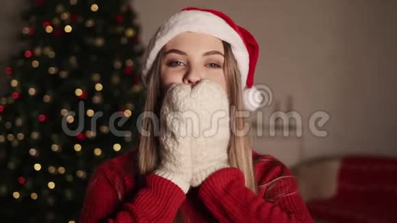 快乐无忧无虑的金发女人在圣诞灯光的背景下亲吻一个戴着圣诞帽的漂亮女孩视频的预览图
