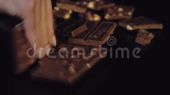 女人用坚果打破黑色巧克力棒特写镜头慢动作视频的预览图