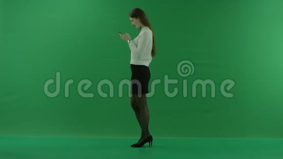 女孩站在她的左边在绿色屏幕上的手机上发短信说一些好东西视频的预览图