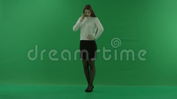 女孩站在一个半转弯的地方看着左边在电话里在绿色屏幕上积极地打手势视频的预览图